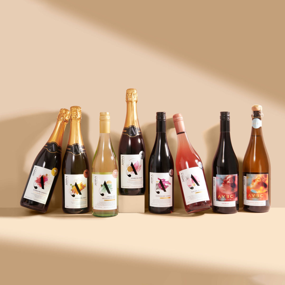 Altina’s full bottle range of non-alcoholic wines arranged in a single row, with sparkling and still bottles displayed side by side. One bottle is elevated on a low plinth at the centre, while the remaining bottles stand directly on the surface, creating a staggered height arrangement against a warm neutral background